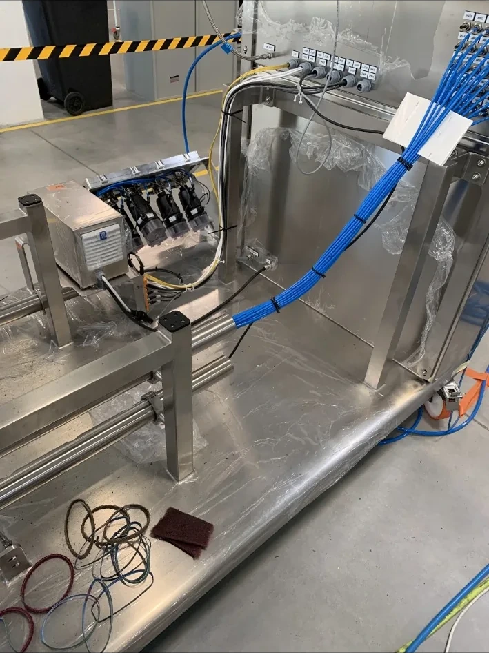 Stainless steel industrial equipment assembly with connected hoses and control components